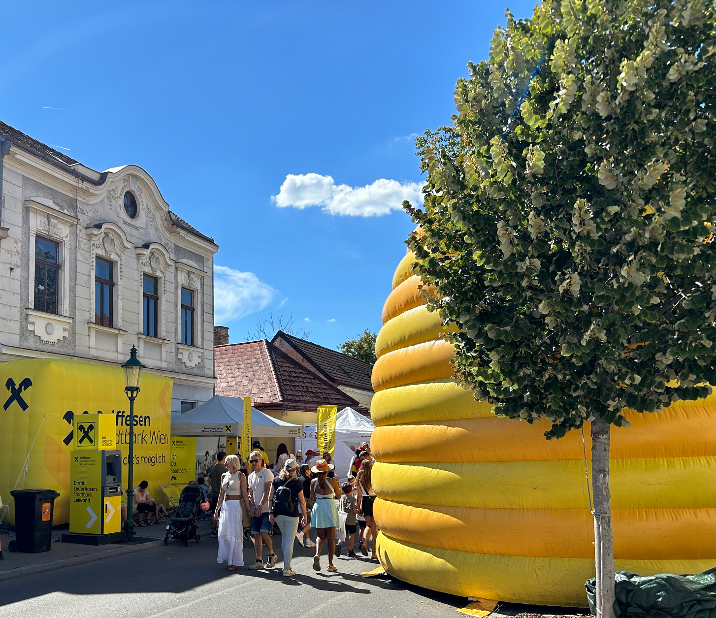 Besucherinnen und Besucher neben dem Raiffeisen-Geldautomaten bei einem Straßenfest